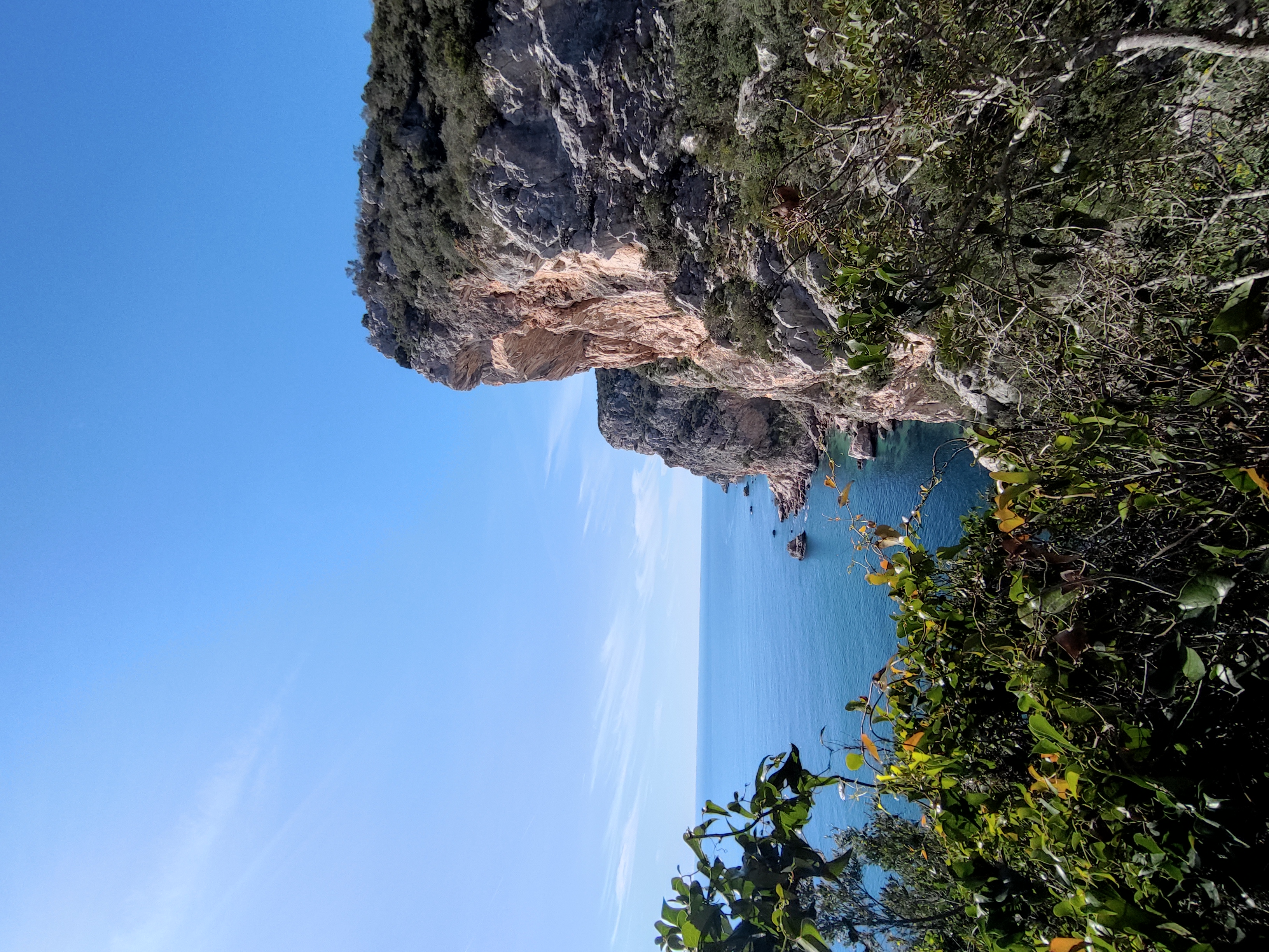 Group of hikers on a clifftop path above a turquoise bay
