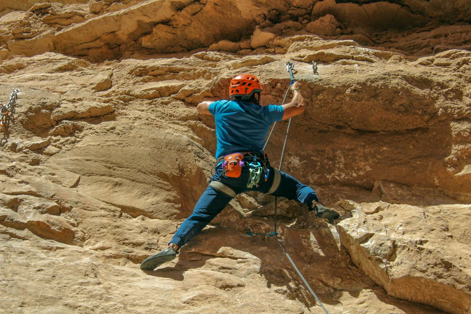 Climber in a helmet clipping the rope into a quickdraw while leading