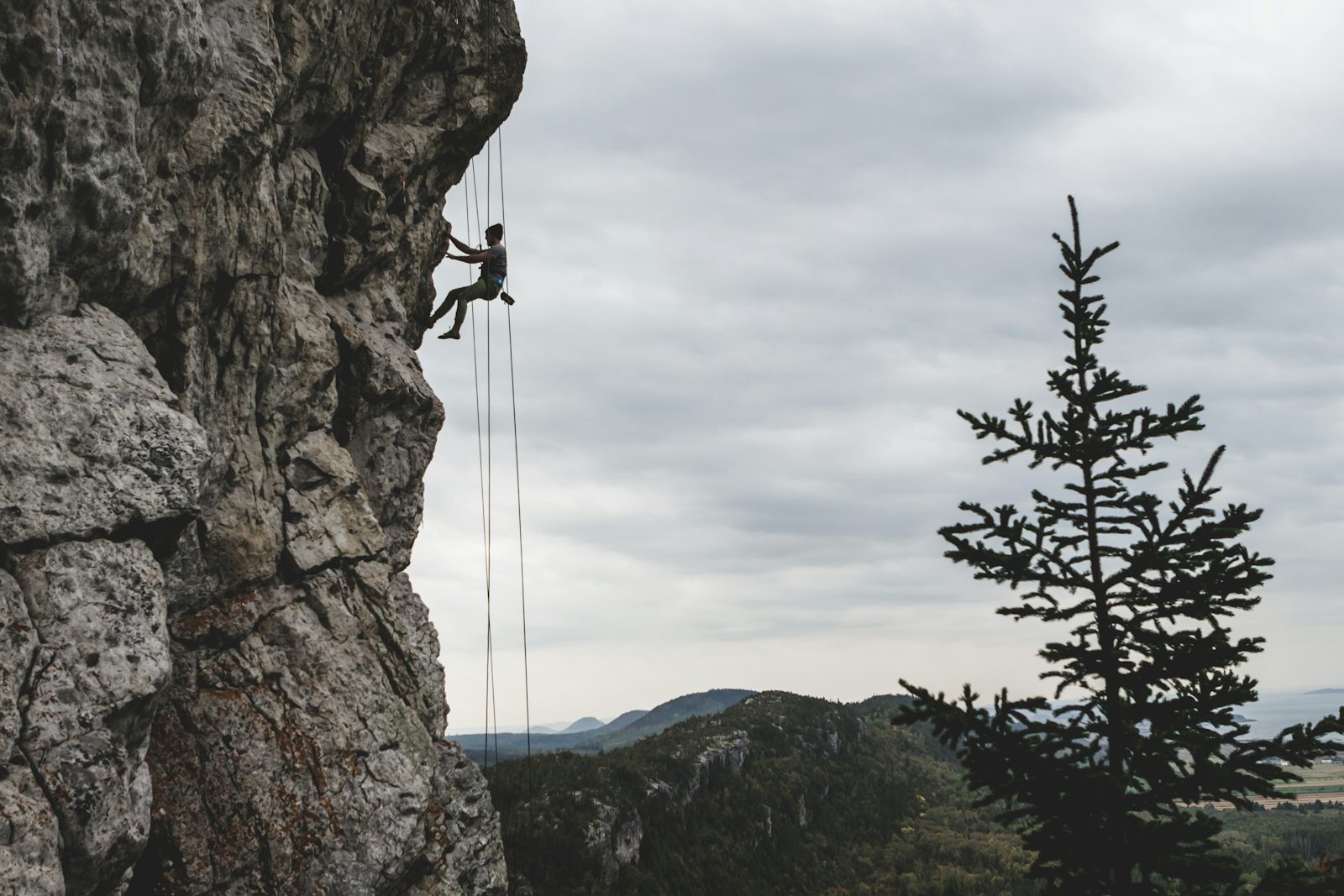 Climber abseiling down a tall rock wall