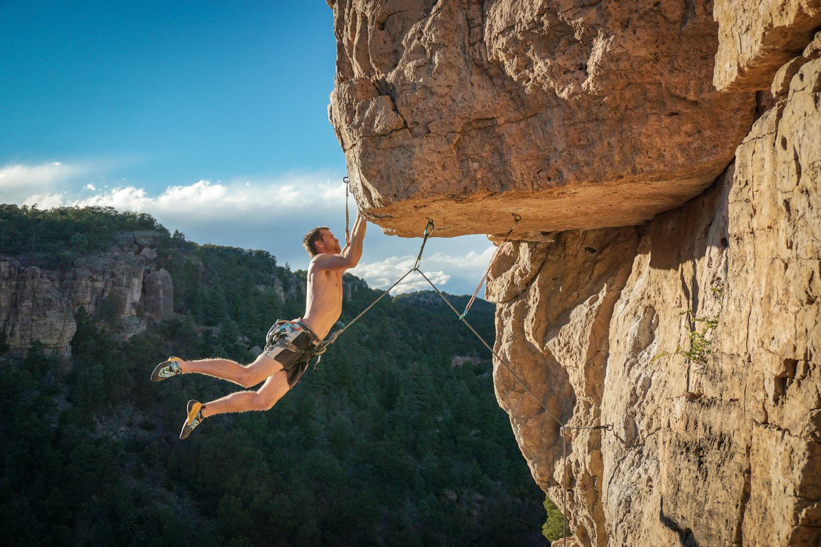 Climber on a rope under an orange limestone overhang