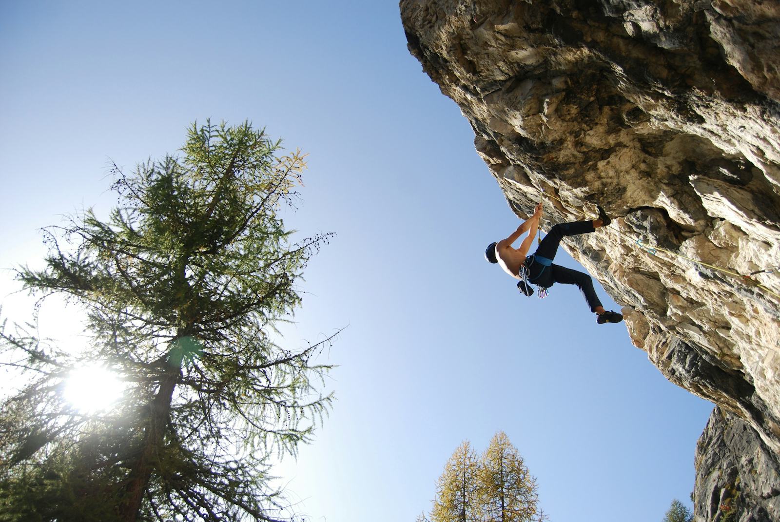 Climber on an overhanging limestone wall against a blue sky
